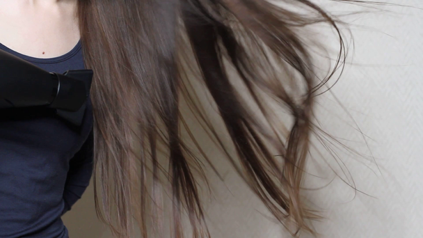 Закрыть видео о том, как женщина сушит волосы черным феном
 - Кадры, видео