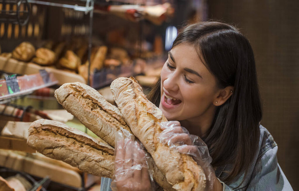 Νεαρή γυναίκα στο σούπερ μάρκετ με φρέσκο ψωμί . - Φωτογραφία, εικόνα