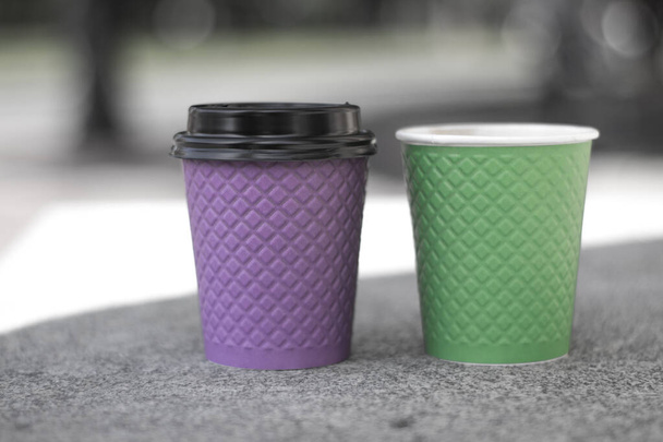 Фіолетовий і зелений паперові чашки кави на плиті. - Фото, зображення