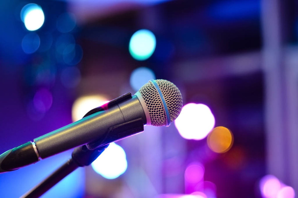 Primer plano del micrófono sobre un fondo desenfocado con luces multicolores en un concierto
 . - Foto, imagen