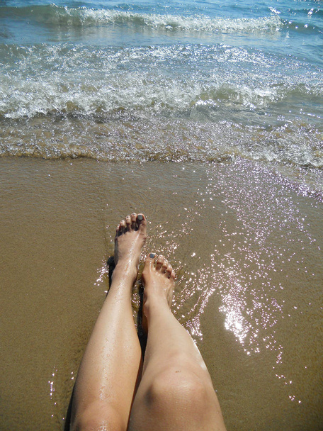 Високий кут зору білошкірих жінок з голими ногами на піску на пляжі
 - Фото, зображення