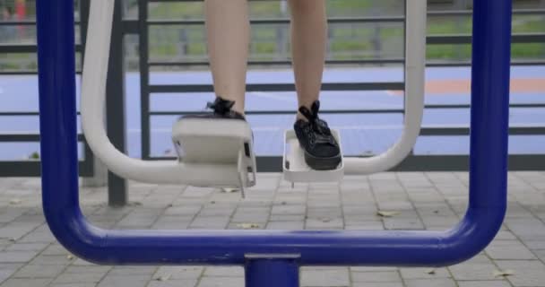 Teenager girl doing exercises for legs on an outdoor sports simulator - 映像、動画