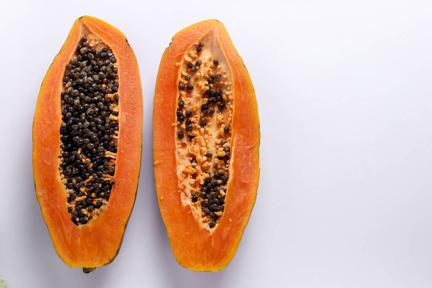 Deux moitiés de papaye mûre sur fond blanc, orientation horizontale, espace de copie
 - Photo, image