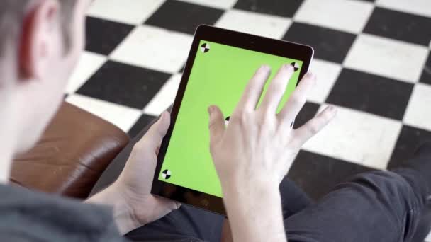 Close-up of man holding tablet and touching green screen. Stock fooatge. Young freelancer uses tablet to work or create projects. Tablet with green screen to insert - Séquence, vidéo