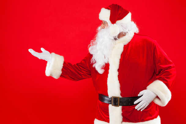 Santa Claus pointing in blank a place, red background - Foto, Bild