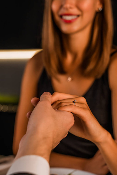 Close up shot of female and male hands togetger with engagement ring on finger, focus on it - Foto, Imagem
