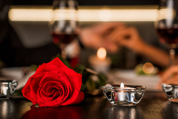 Romantic dinner date at night with focus on red rose and candles on the foreground - Photo, Image