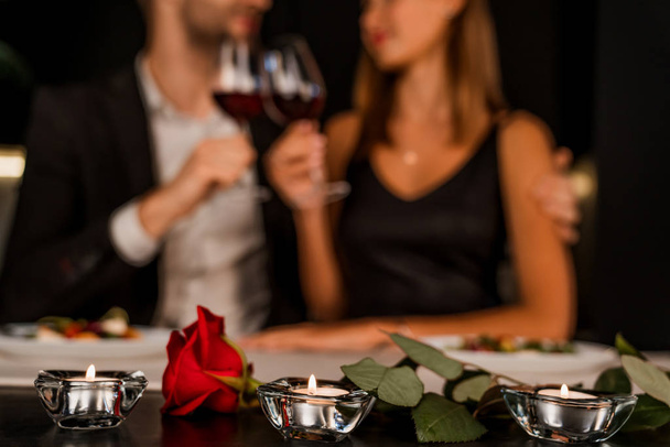 Romantic dinner date at night with focus on rose and candles - Foto, afbeelding