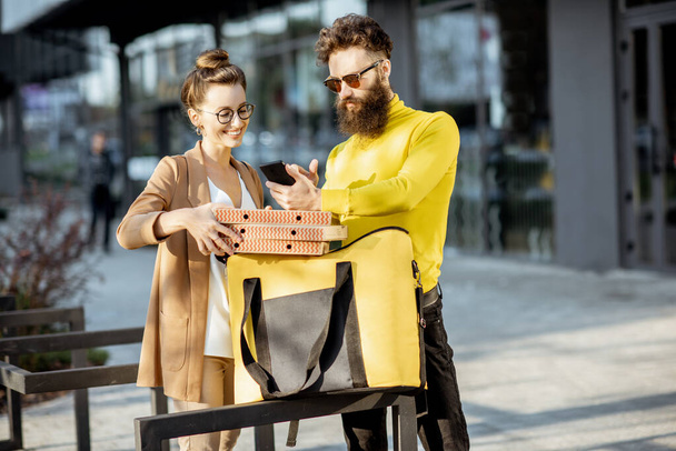 Мужчина доставляет пиццу молодой женщине-клиенту
 - Фото, изображение