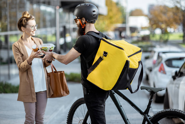 Courier delivering food to a business woman outdoors - Photo, Image