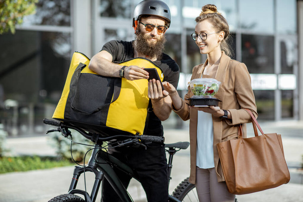 Courier delivering food to a business woman outdoors - Valokuva, kuva