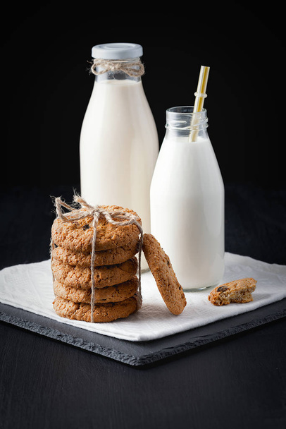 Oatmeal cookies and milk drinks on a black table. - Фото, изображение