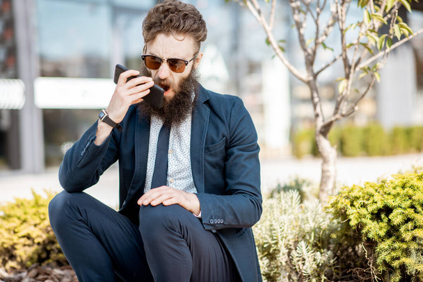 Emotional businessman talking phone outdoors - Fotó, kép
