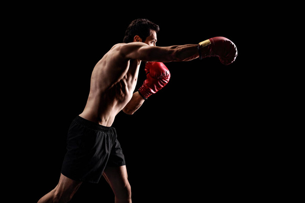 Μυώδης άνθρωπος γροθιά με γάντια πυγμαχίας - Φωτογραφία, εικόνα