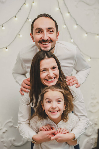 Leuke familie speelt rond op kerstochtend, grappige vader moeder en dochter blijven in de positie waar hun hoofden boven elkaar, als een toren. - Foto, afbeelding