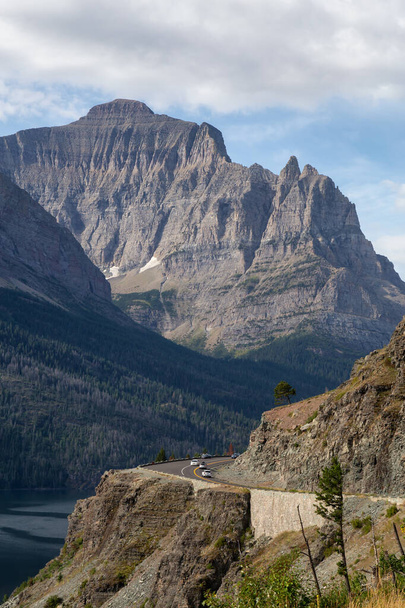 Beautiful View of Scenic Highway with American Rocky Mountain Landscape in the background during a Cloudy Summer Morning. Taken in Glacier National Park, Montana, United States. - 写真・画像