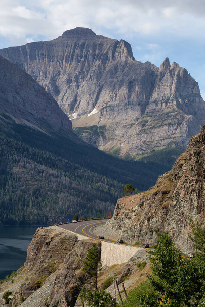 Beautiful View of Scenic Highway with American Rocky Mountain Landscape at the Cloudy Summer Morning (англійською). Бере участь у Національному парку Льодовик "є (штат Монтана, США).. - Фото, зображення