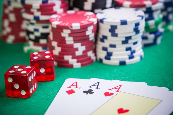 drei Asse und rote Würfel mit Pokerchips am grünen Tisch - Foto, Bild
