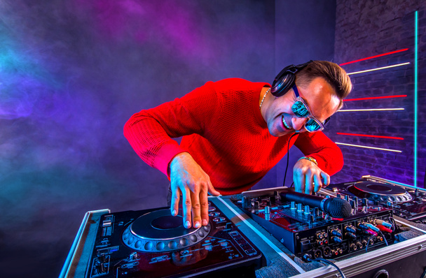 Весёлый ди-джей микширует треки на проигрывателе в ночном клубе
 - Фото, изображение