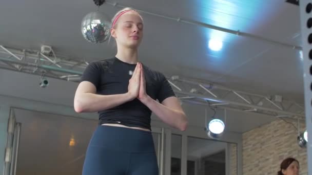 Közelkép a sportos fiatal gyönyörű nő meditáló beltéri, összpontosítani karok Namaste gesztus - Felvétel, videó