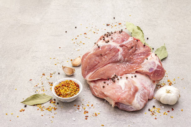 Raw pork shoulder with spices. Bay leaf, garlic. On a stone background, copy space. - Photo, Image