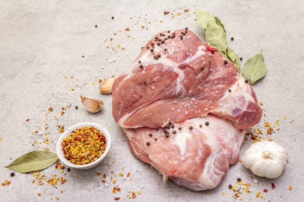 Raw pork shoulder with spices. Bay leaf, garlic. On a stone background, close up. - Photo, Image