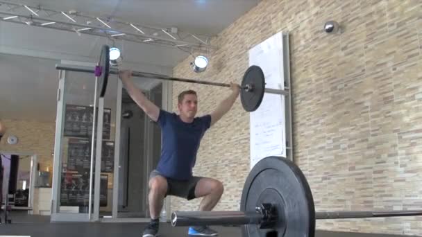 Sportlicher Mann trainiert Kniebeugen mit Langhantel über dem Kopf - Filmmaterial, Video