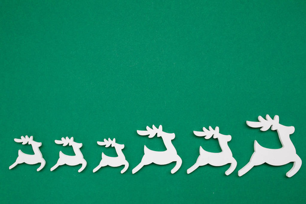 Dřevěné vánoční hračka Jeleni na tmavě zeleném izolovaném pozadí s kopírovacím prostorem. Veselé Vánoce a šťastný nový rok. Minimalistický styl. Byt ležel, pohled shora, silvestrovský plakát - Fotografie, Obrázek