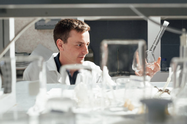 αρσενικός επιστήμονας διεξάγει χημικά πειράματα με υγρά στο ιατρικό εργαστήριο - Φωτογραφία, εικόνα
