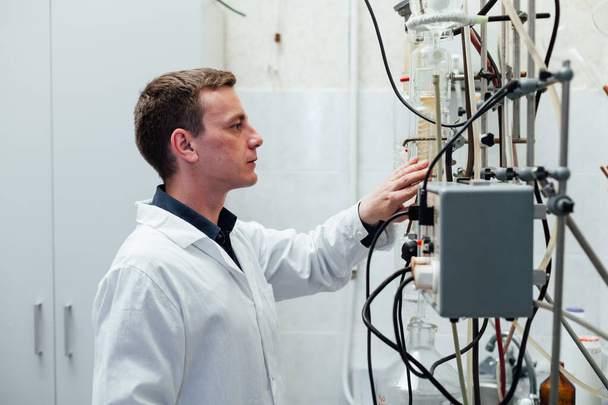 mannelijke wetenschapper voert chemische experimenten met vloeistoffen in medisch laboratorium - Foto, afbeelding