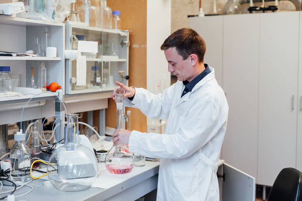 ученый-мужчина проводит химические эксперименты с жидкостями в медицинской лаборатории
 - Фото, изображение