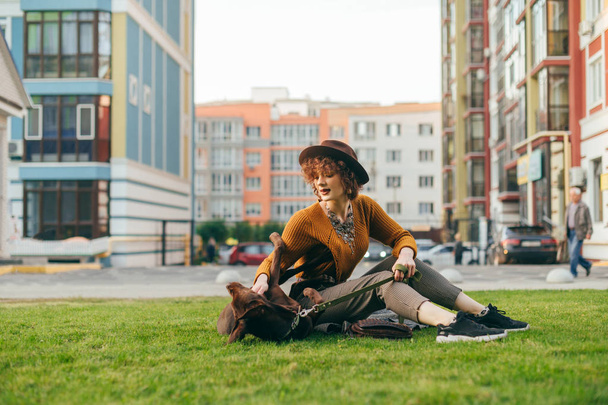Stylová dívka hraje s krásným hnědým štěňátkem na trávníku, s - Fotografie, Obrázek
