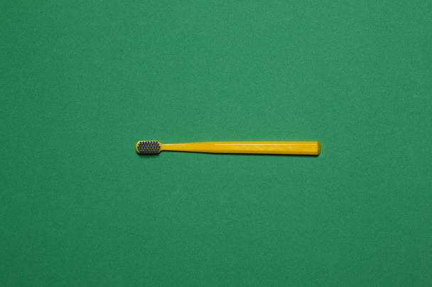 yellow toothbrush on green background - 写真・画像
