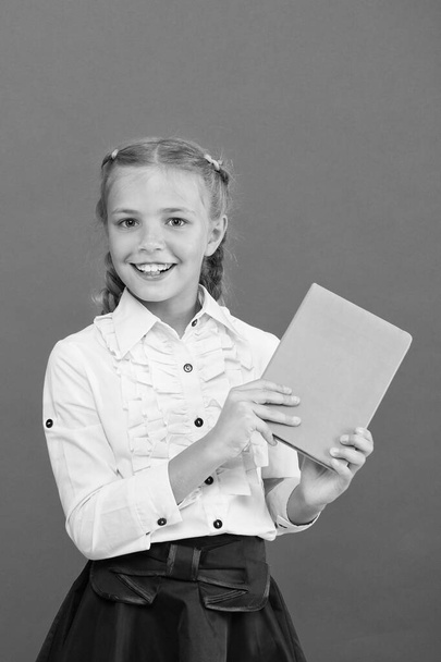 All of her knowledge is from book. Adorable small girl holding book on red background. Cute little child with book knowledge in hands. Knowledge skills. Knowledge day or September 1, copy space - Foto, Imagem