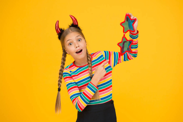 Preparing for party. Start this party. Party attributes. Playful demon girl. Small child with red horns and eyewear. Accessories for carnival. Girlish temper. Cute but dangerous. Halloween concept - Foto, afbeelding