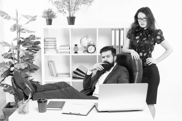 Typical office life. Man bearded hipster boss sit in leather armchair office interior. Boss and secretary girl at workplace. Relations at work. Business people and staff concept. Lazy boss office - Photo, image