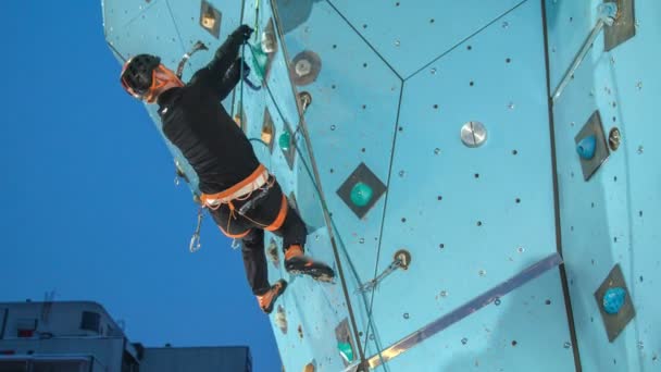 Un hombre pone una cuerda más alta en la pared de escalada cuando está alcanzando alturas más altas
. - Metraje, vídeo