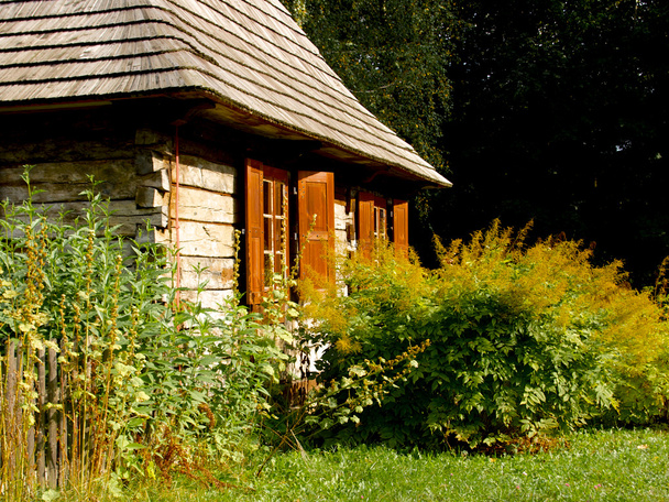 Pared de madera cabaña con ventanas, persianas y jardín en frente
 - Foto, imagen