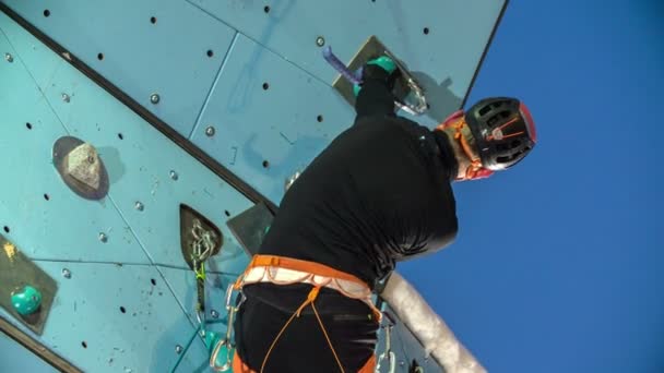Een man die heeft geklommen in de klimwand is bijna naar de top geklommen, naar het plafond in de sportschool.. - Video