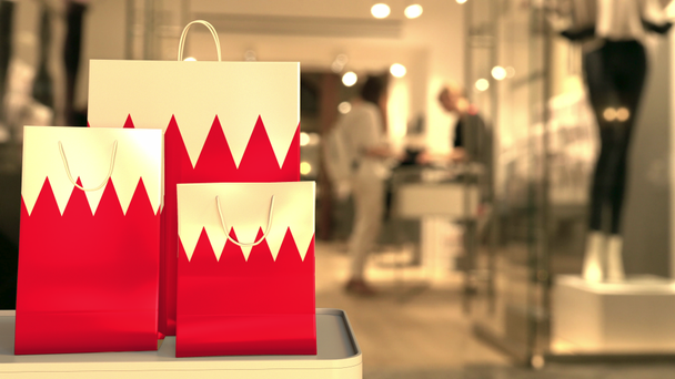 Paper shopping bags with flag of Bahrain against blurred store. Bahraini shopping related clip - Footage, Video