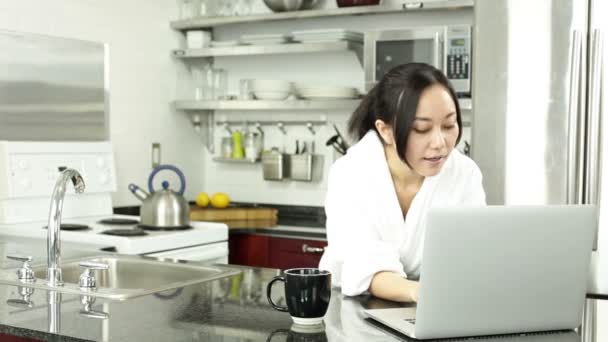 Asian girl with a laptop in the kitchen - Footage, Video