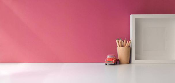 Moderne werkruimte met mock up frame en kopieer ruimte op witte houten tafel en roze wand achtergrond  - Foto, afbeelding