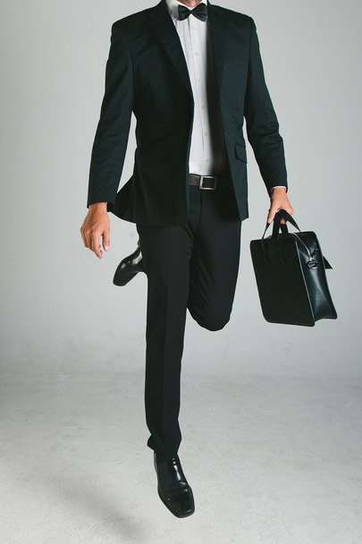 κομψό νεαρό άνδρα με μαύρο κοστούμι και χαρτοφύλακα. - Φωτογραφία, εικόνα