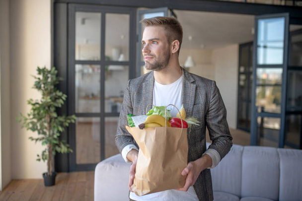 Blue-eyed young businessman holding bag after shopping - Foto, Imagem