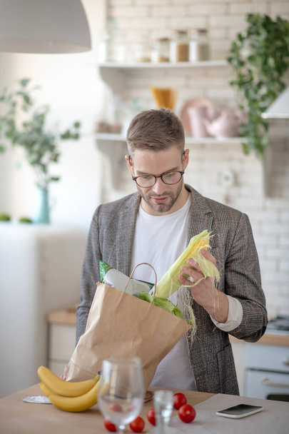 Man taking corn out of bag after going to supermarket - Foto, imagen