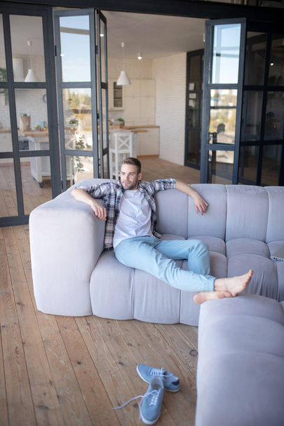 Barefooted man chilling on sofa in the living room - Foto, Imagen