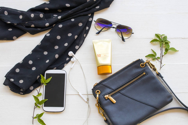 sunscreen spf50 health care for skin face with sunglasses ,shoulder bag ,mobile phone and black scarf accessories of lifestyle woman relax arrangement flat lay style on background white wooden - 写真・画像