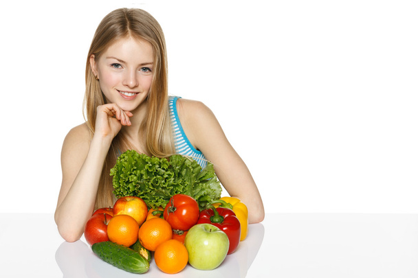 Kobieta siedząca przy stole z warzywami - Zdjęcie, obraz