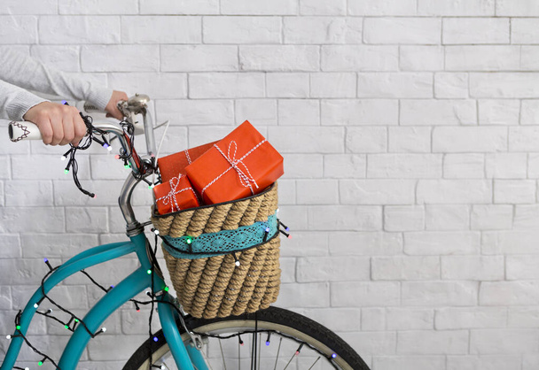 Felismerhetetlen nő biciklizik karácsonyi ajándékokkal - Fotó, kép