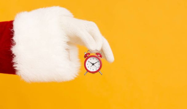 Santa main tenant petit réveil rouge avec le temps sur orange
 - Photo, image